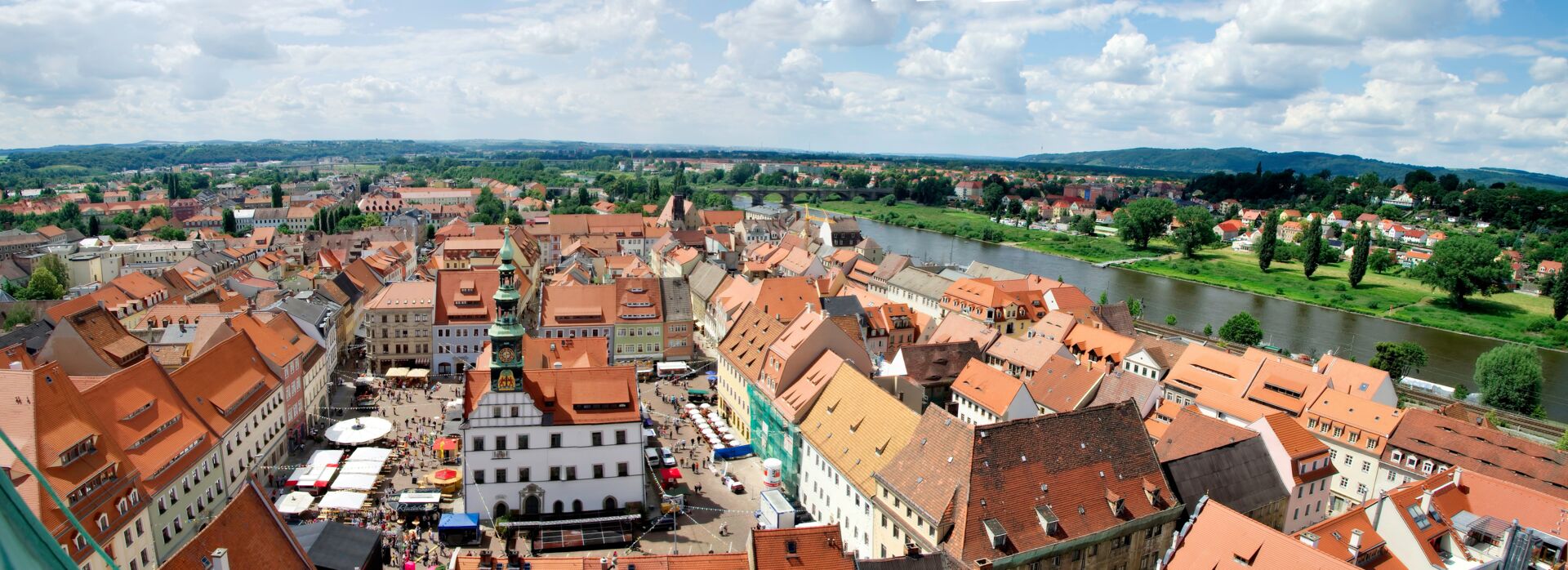 Eine Aufnahme einer Stadtansicht mit einer Kirche, einem Fluss und roten Dächern